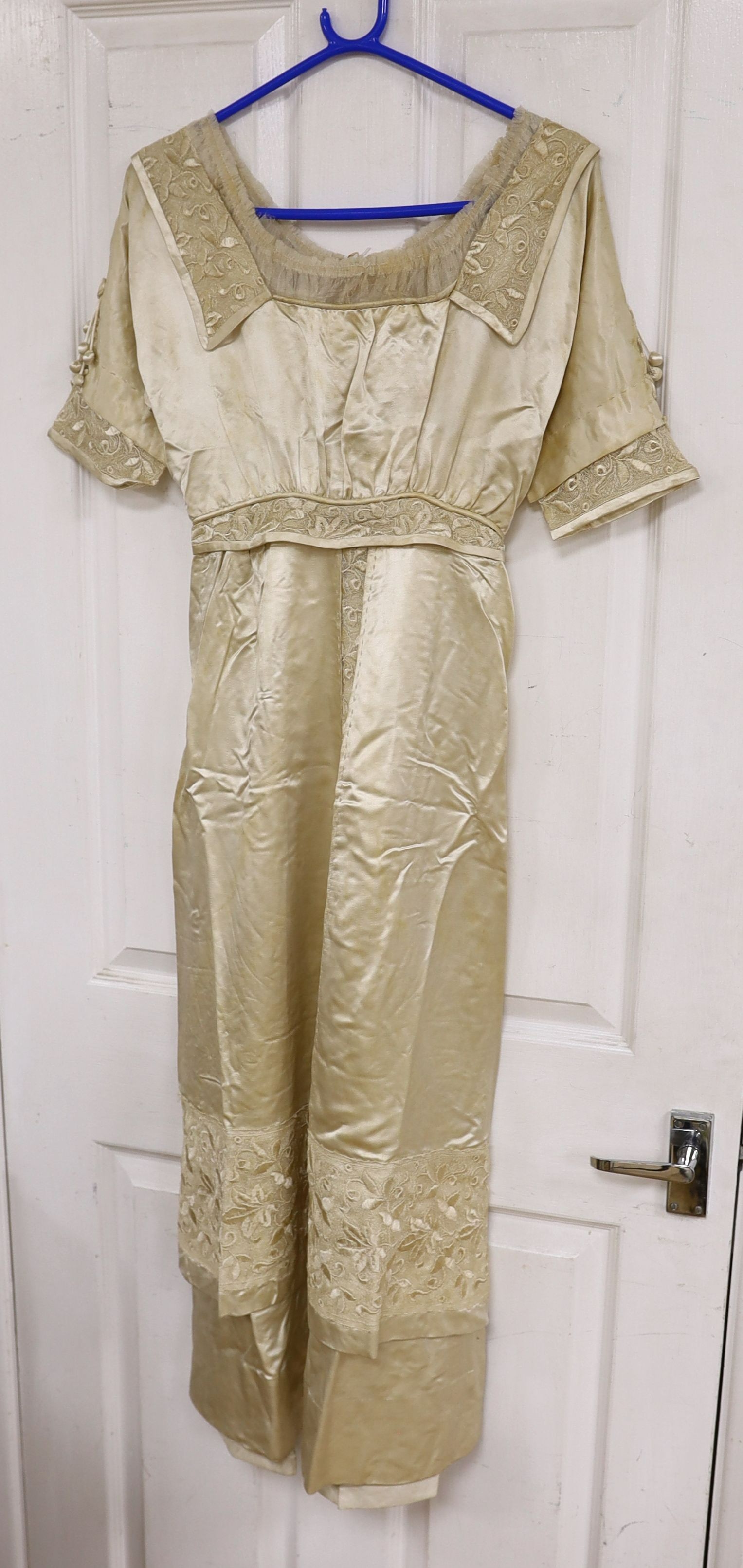 An Edwardian cream satin lady's dress with embroidered panels to base,sleeves front and collar